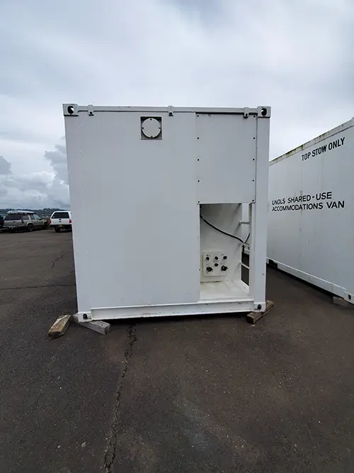 The white exterior of a portable lab van in front of a building.