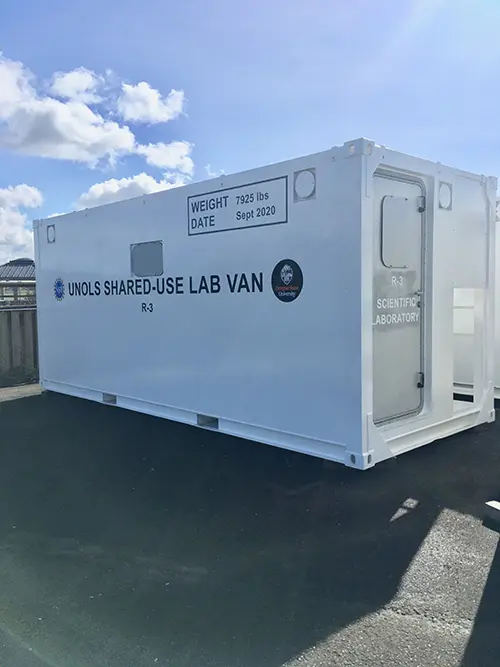 The white exterior of a lab van with a silver door on the end.