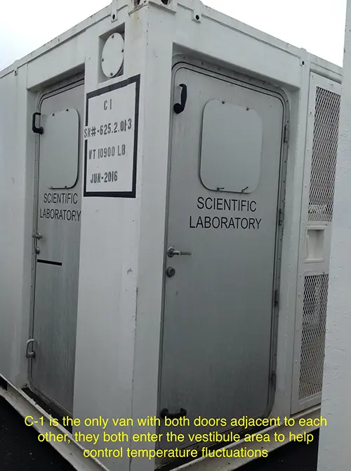 The white exterior of a portable lab van showing two silver doors adjacent to each other.