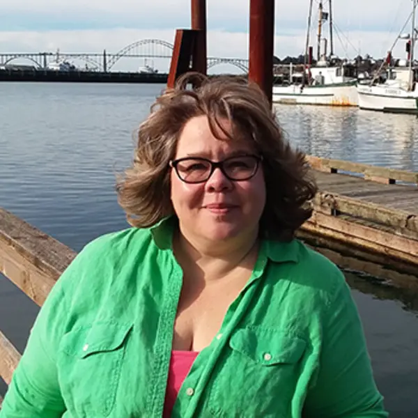 A person stands in front of a boat marina and smiles at the camera.