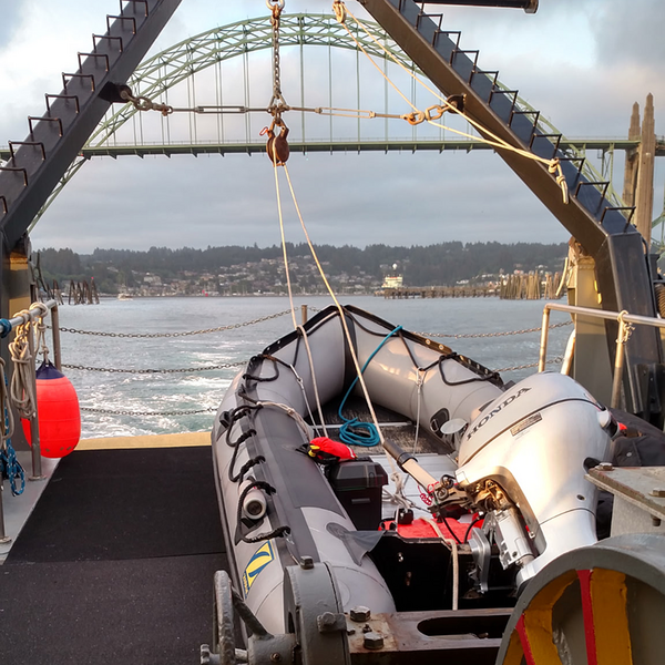 A ridged hull boat sits on the deck of a larger vessel. 