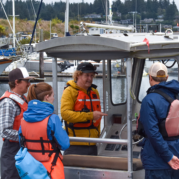 People gather on a small metal boat with a small cabin.
